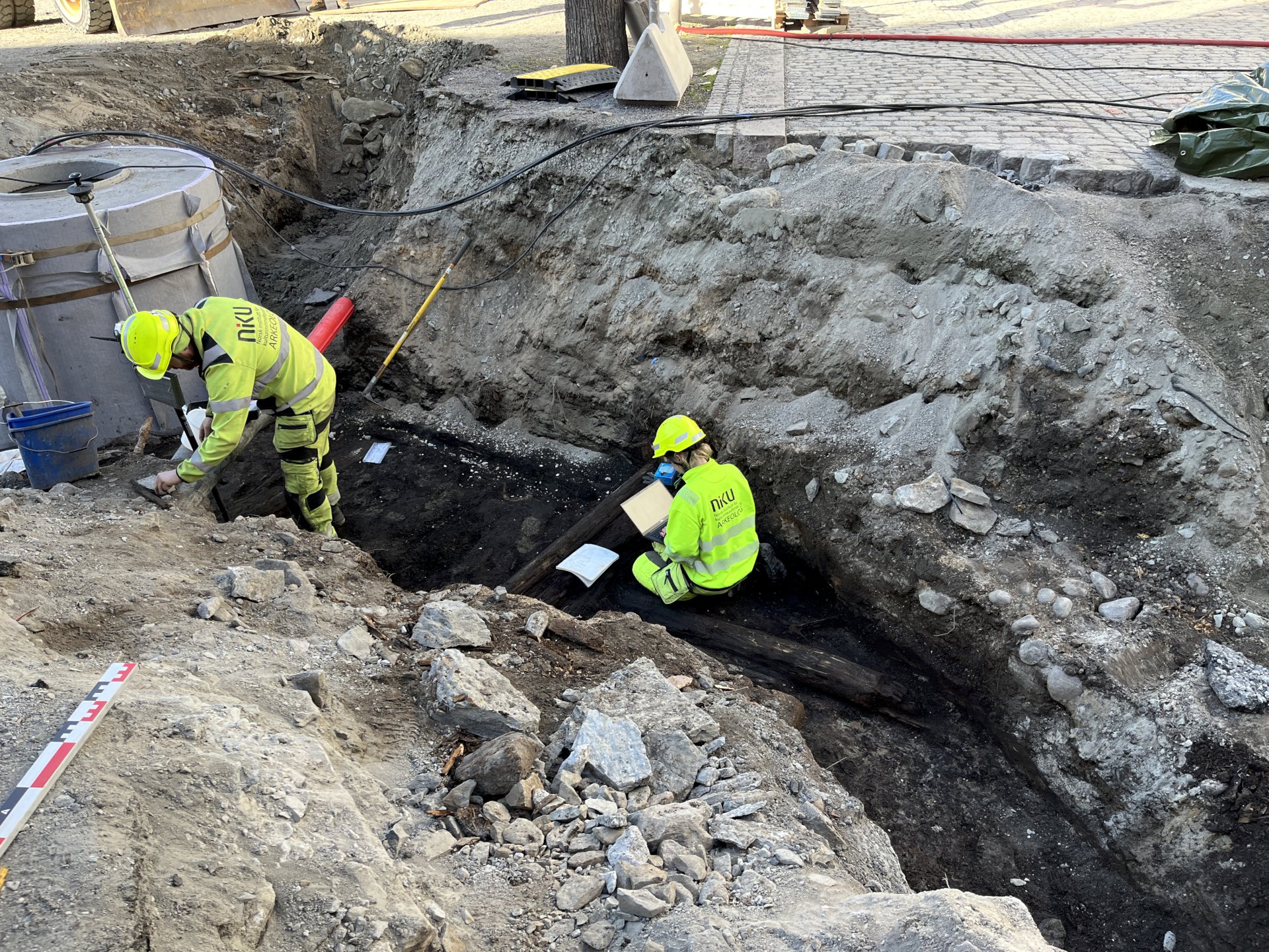 To personer undersøker et gammel tredekke som er gravd fram.