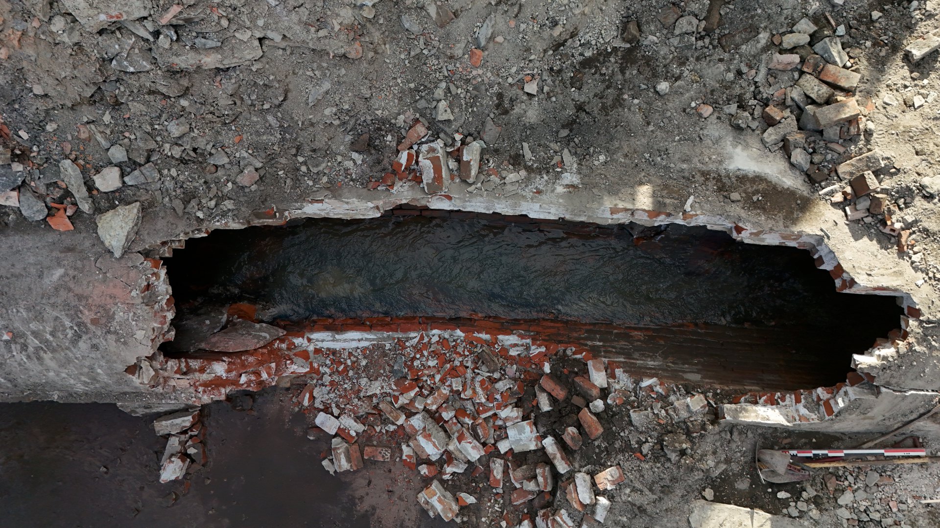 en åpen teglsteinkulvert hvor det renner vann