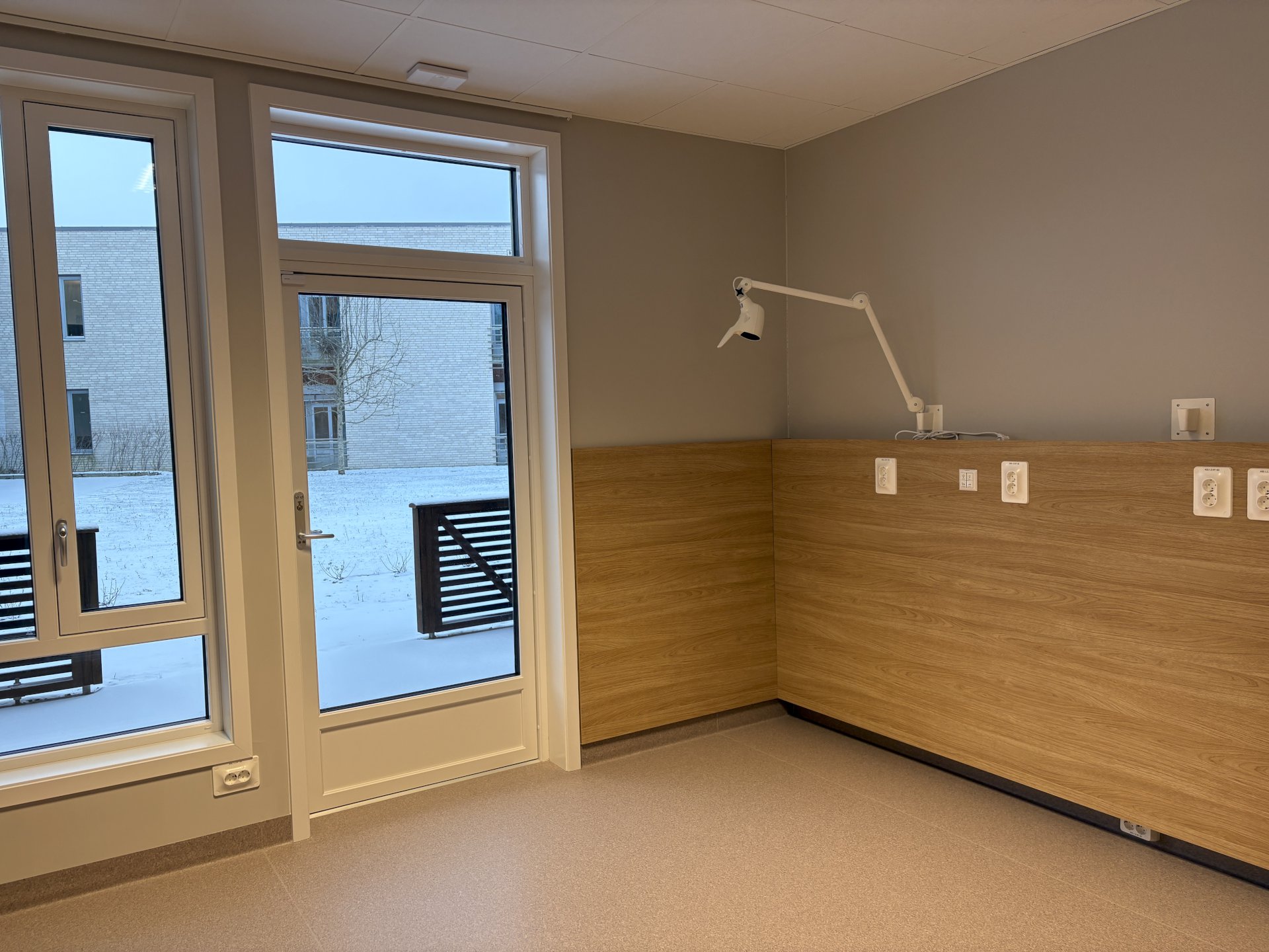 sykehjemsrom med vinduer og varandadør.