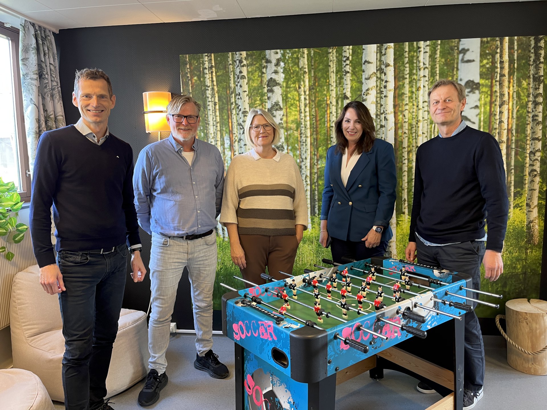 Fem personer står i et rom