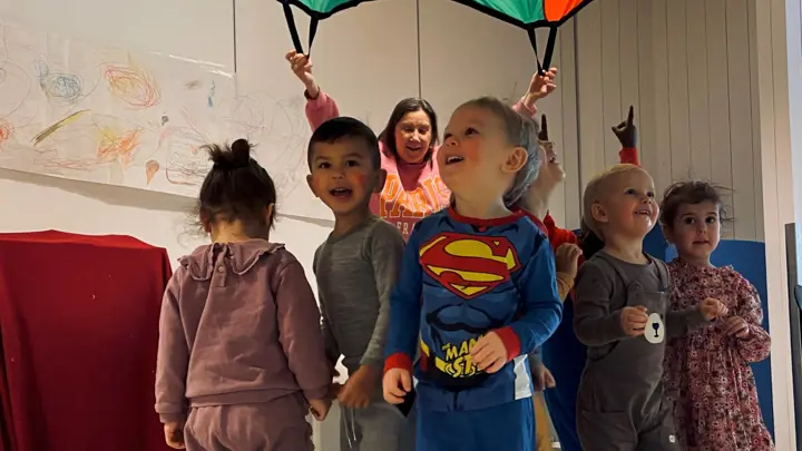 Barn som leker med fargerik fallskjerm.