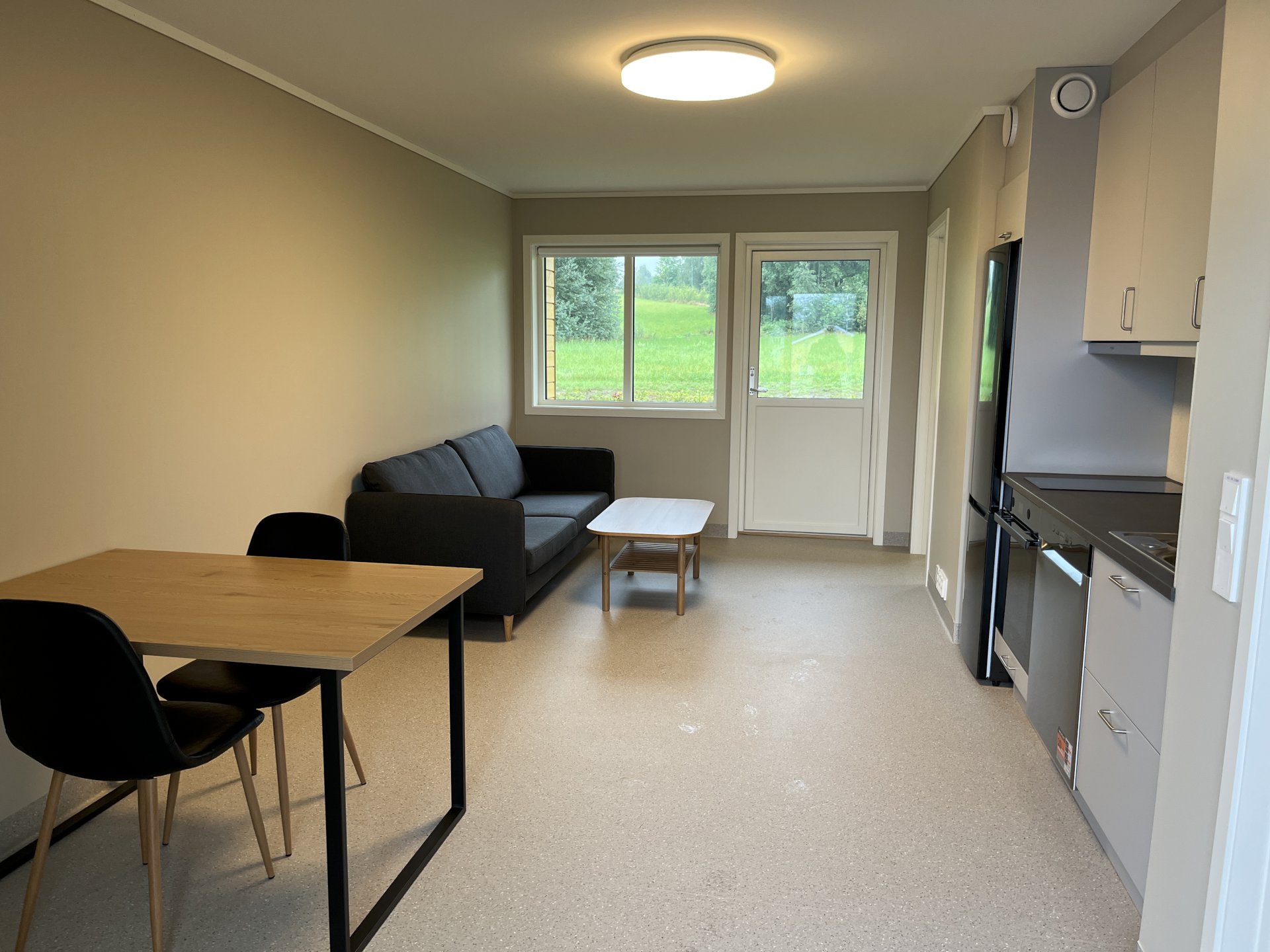 boligrom med bord, stol, sofa og kjøkkeninnredning.